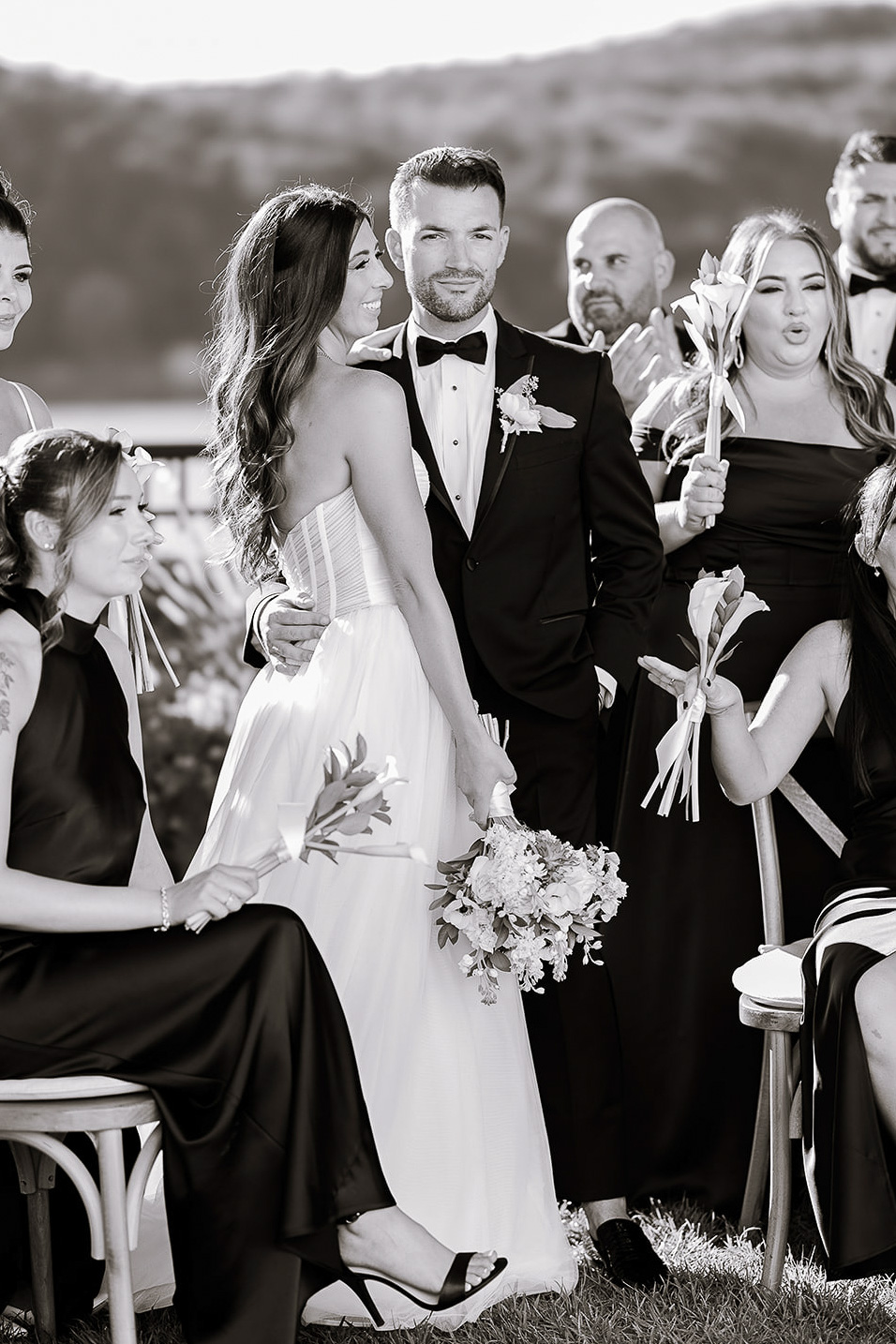 Black and white wedding portrait of bride and groom with bridal party holding flowers outdoors in New York, NY.