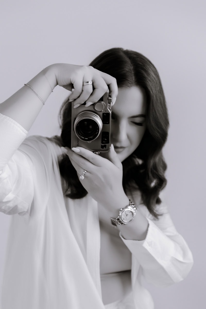 Candid portrait of wedding photographer Zina Bolotnova holding a Contax G2 film camera.