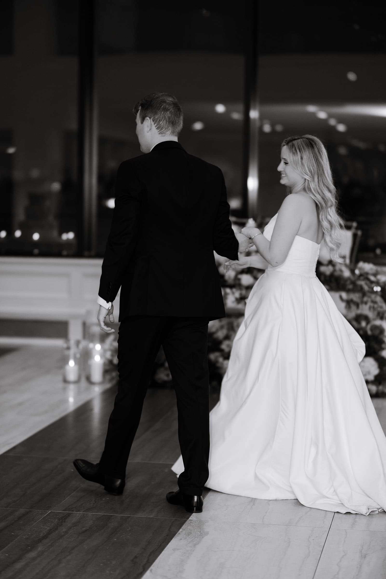 Bride and groom holding hands dancing indoors at Hudson House, Jersey City, with candles and floral decor in background.