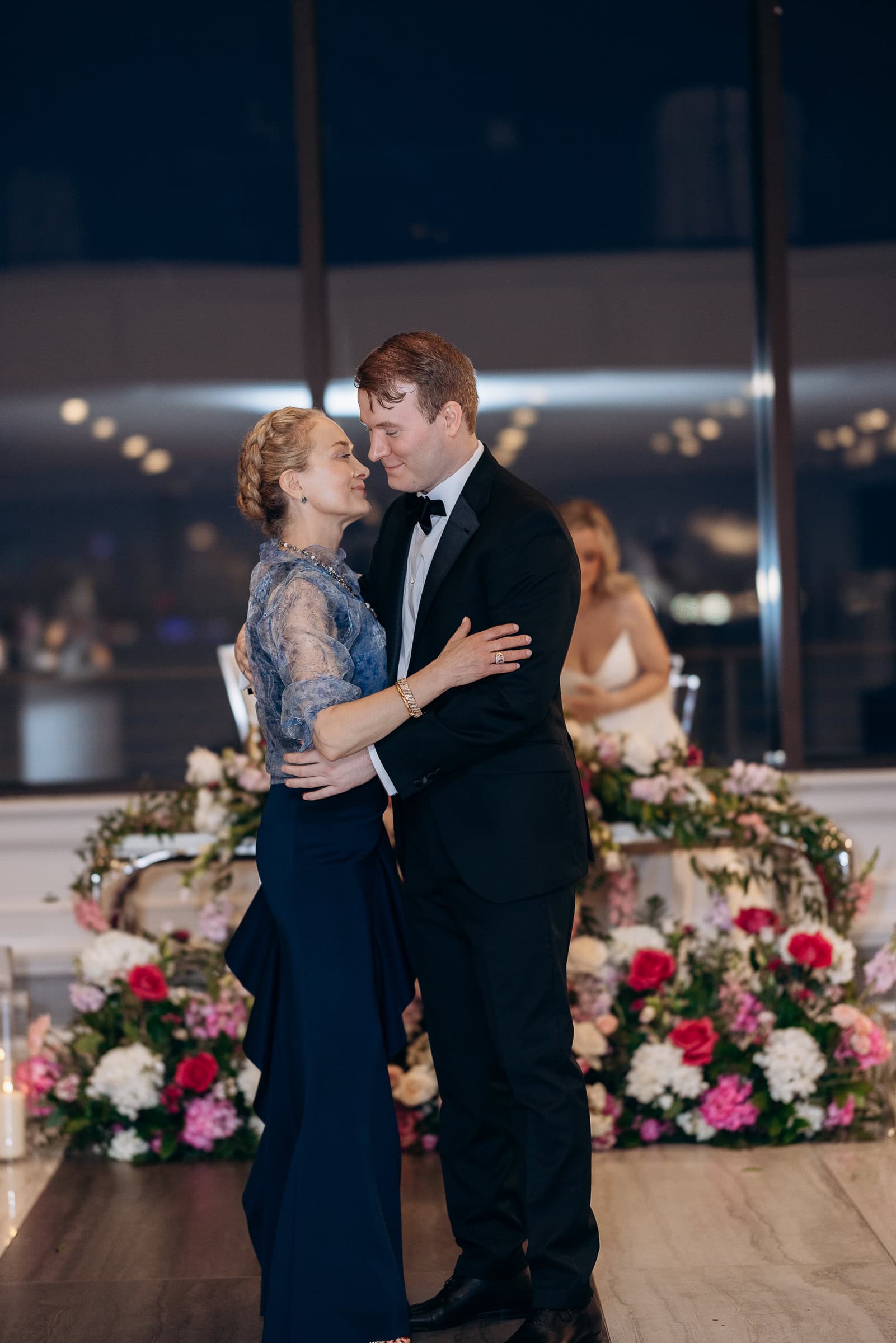 Couple in elegant attire dancing closely surrounded by vibrant floral arrangements at Hudson House, Jersey City, NJ.