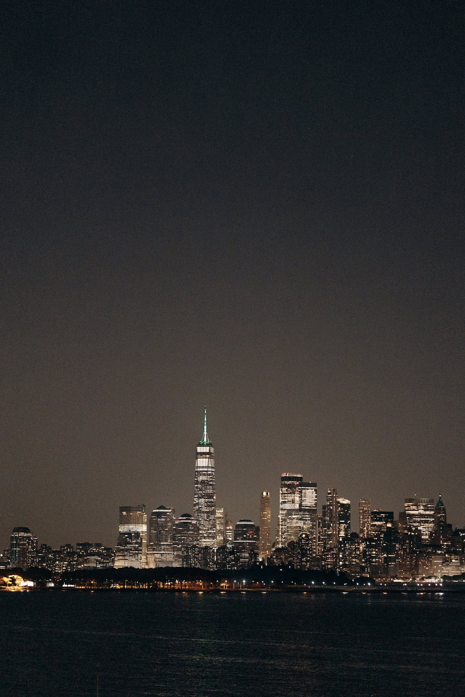 Nighttime view of Manhattan skyline with One World Trade Center lit up, seen from Hudson House in Jersey City, NJ.