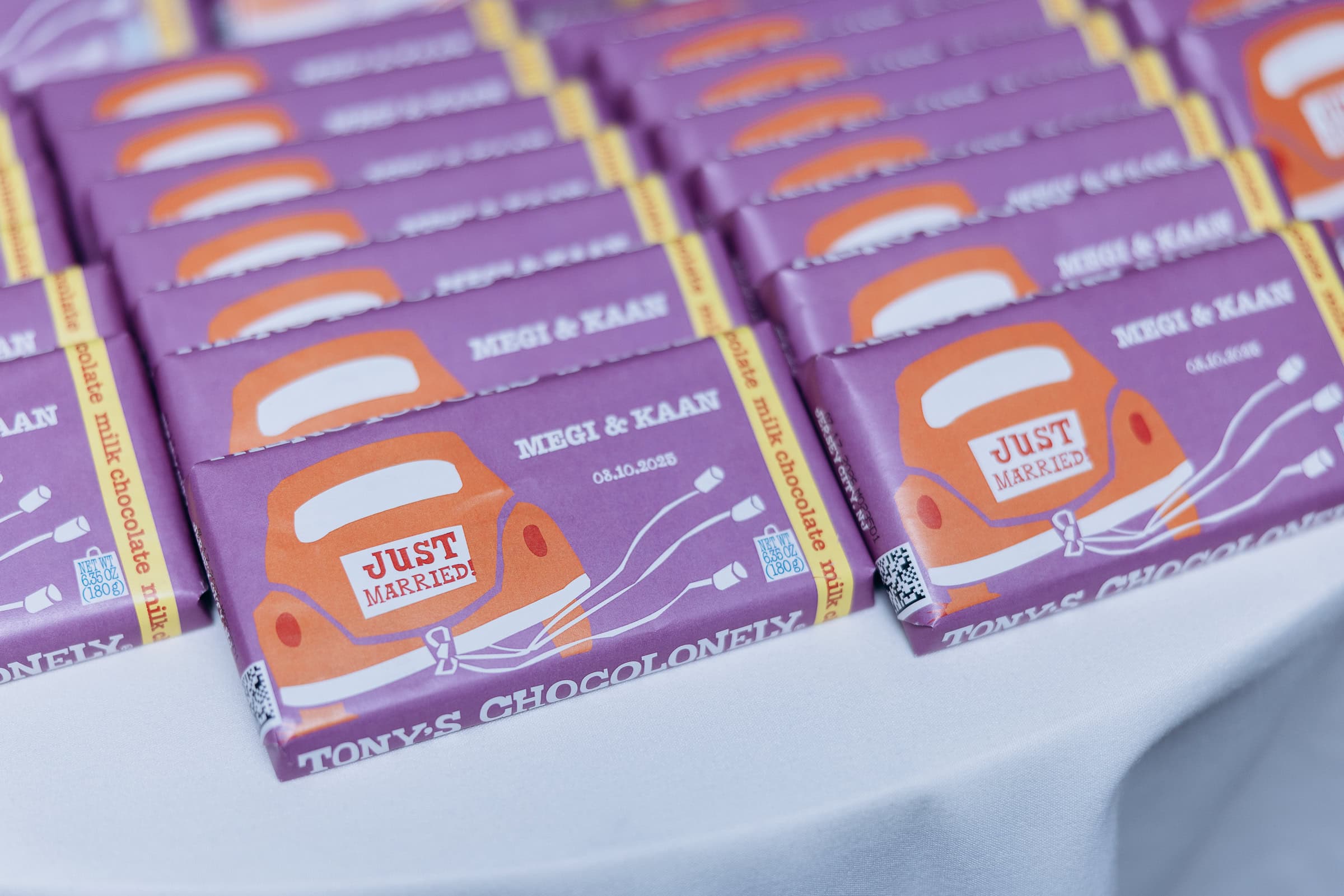 Close-up of custom Tony's Chocolonely milk chocolate bars wrapped in purple with a vintage car and "Just Married" sign, personalized with Megi & Kaan and wedding date.