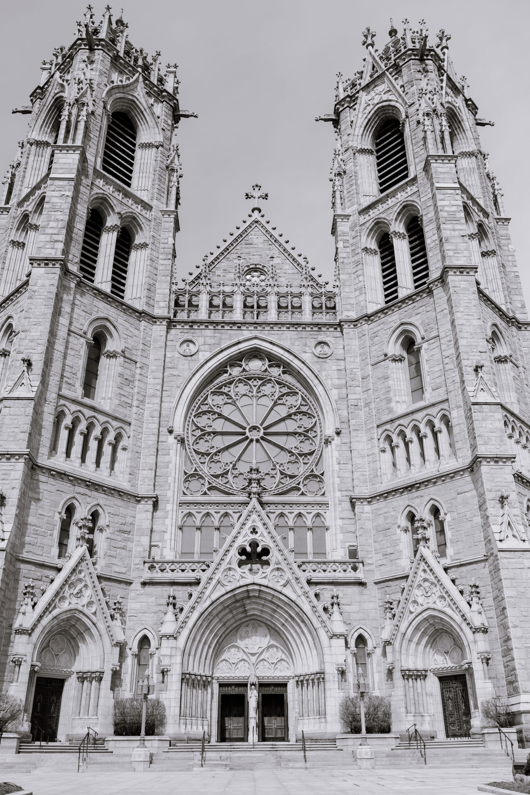 Close-up view of the Gothic Revival facade of The Cathedral Basilica of the Sacred Heart with twin towers, rose window, and ornate stone carvings.