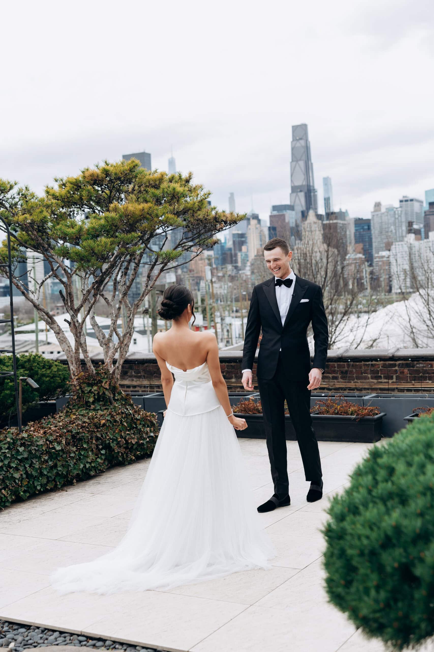Bride and groom share a first look on a terrace at The Foundry, with the Manhattan skyline behind them on an overcast spring day.