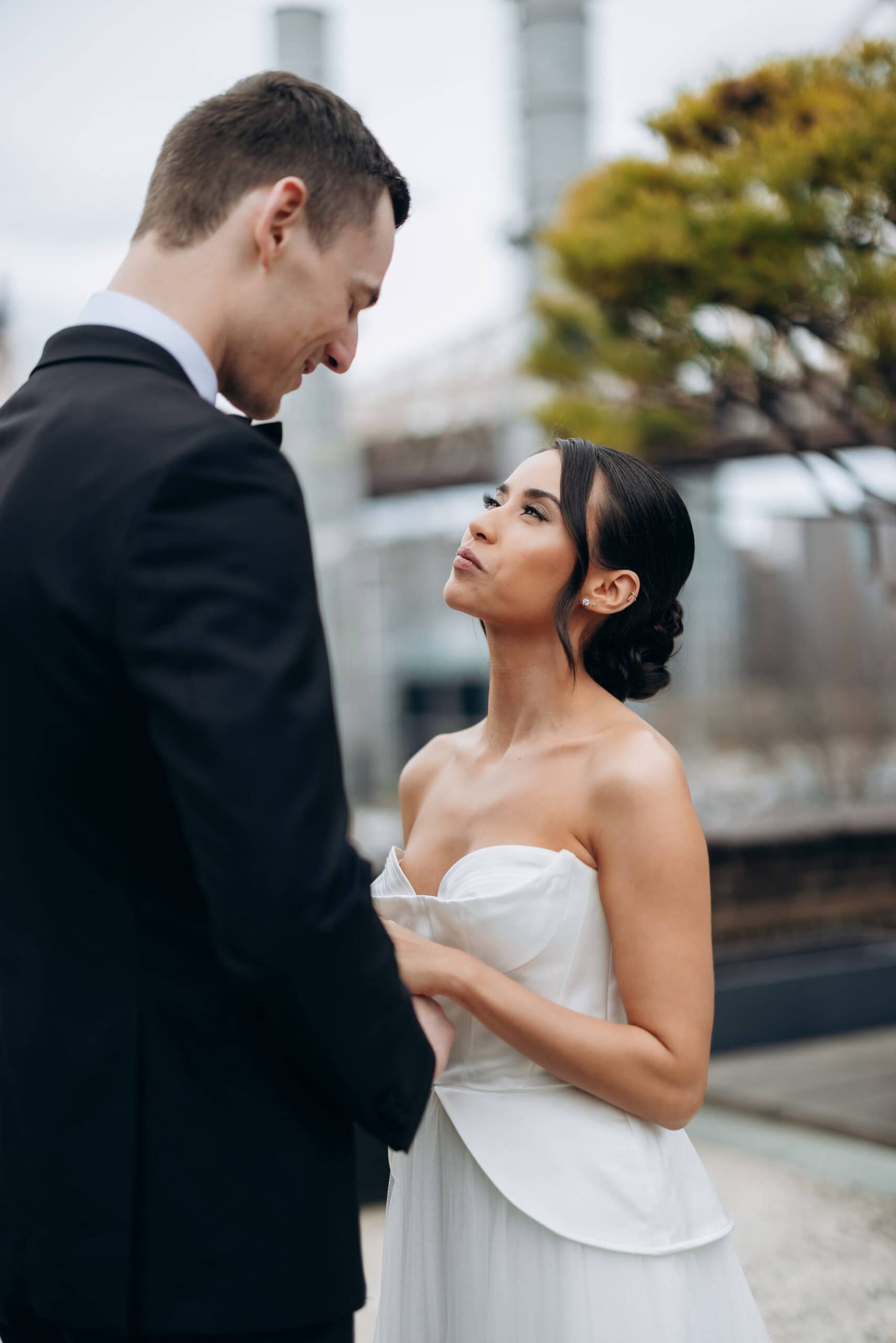 Bride in a strapless white gown looks up at groom in a black tuxedo during an intimate outdoor wedding portrait at The Foundry.