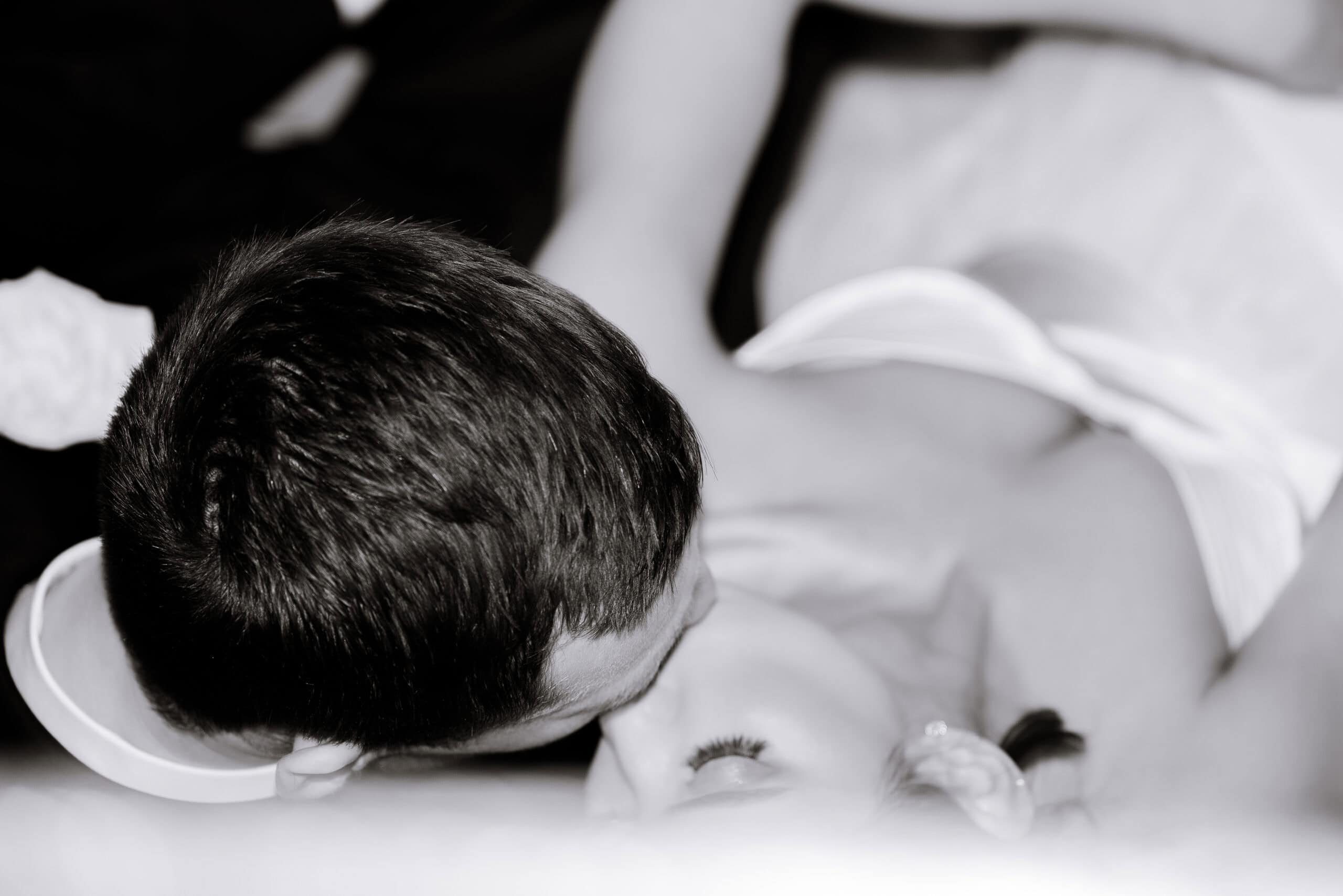 Black-and-white close-up of a couple reclining together, one partner leaning in toward the other's face, photographed in soft focus at The Foundry.