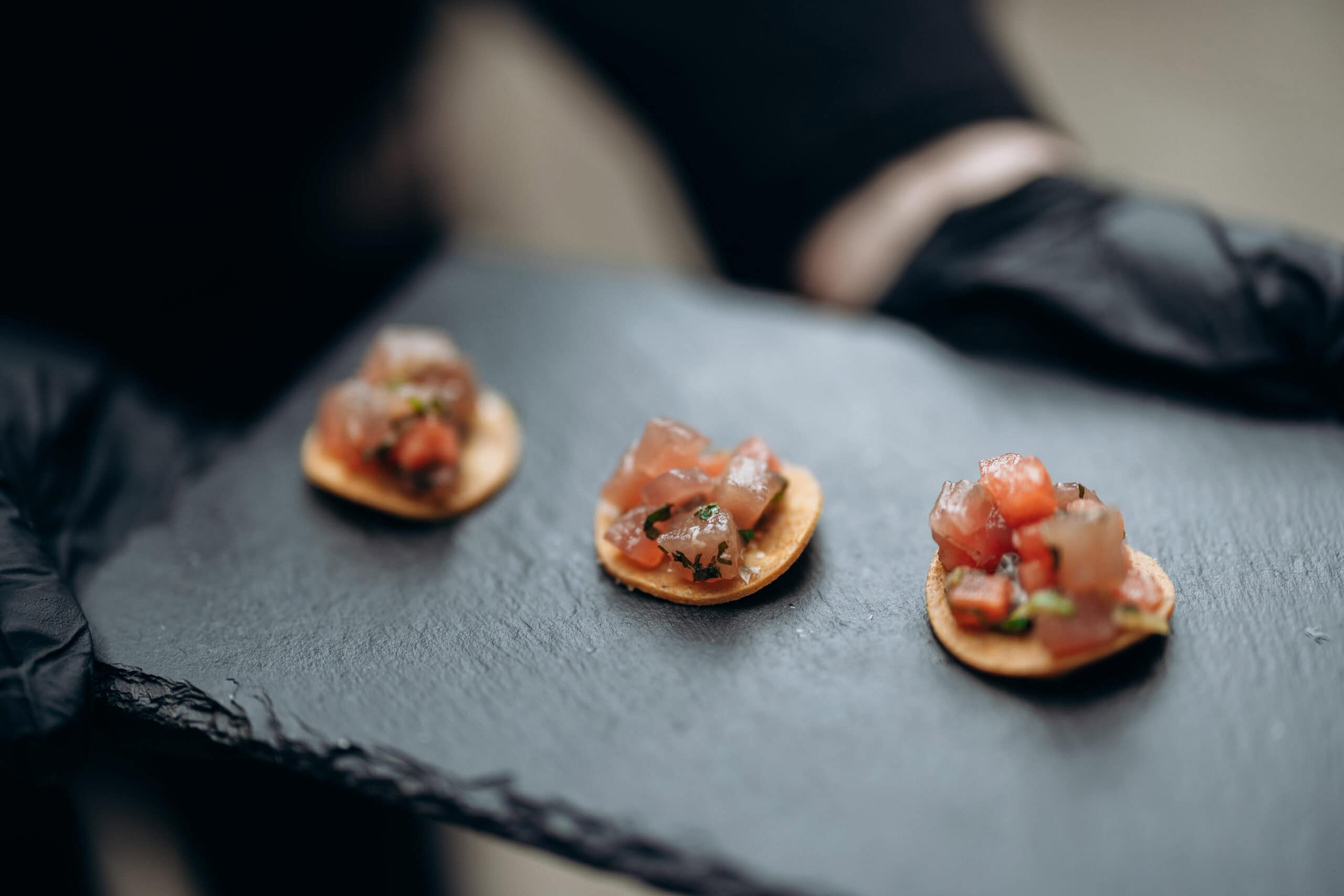 Close-up of three bite-size canapés on a black slate serving tray at The Foundry, photographed with shallow depth of field during a wedding reception.