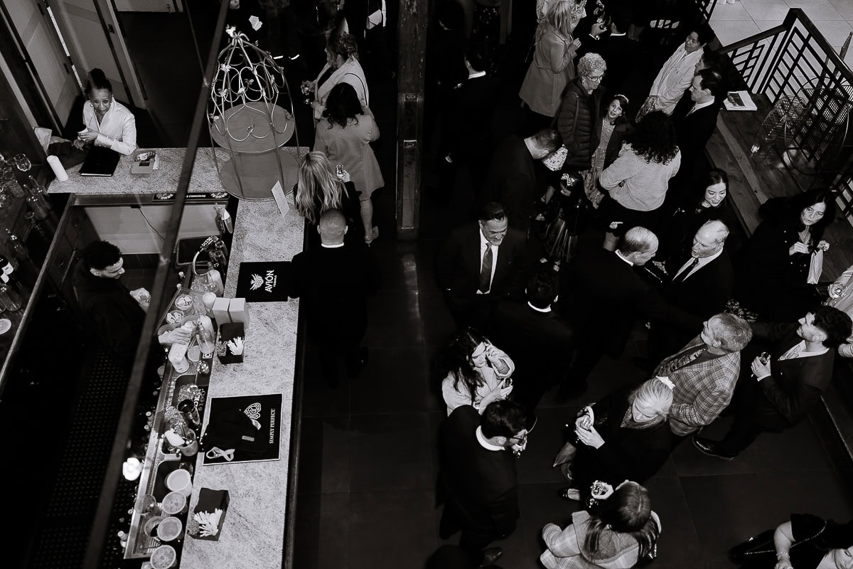 Overhead black and white photo of guests conversing and enjoying drinks around a marble bar at an elegant event at The Stone House, Warren, NJ.