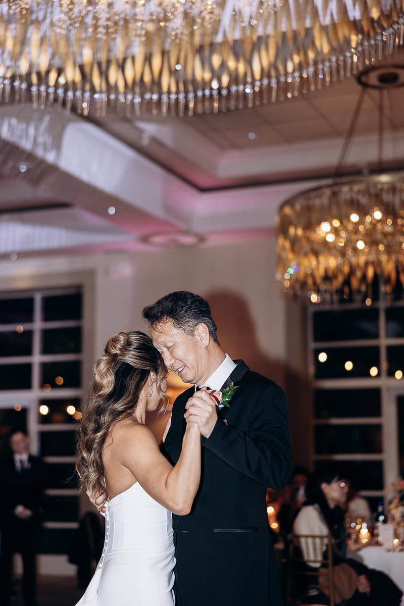Bride and father sharing an intimate dance under warm chandelier lighting at a wedding reception in The Stone House, Warren, NJ.