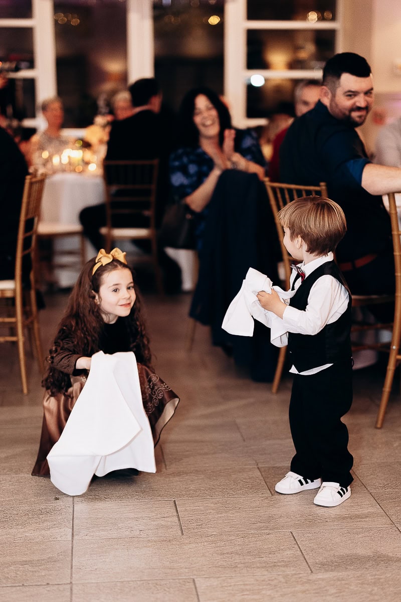 Young girl and boy in formal wear holding white napkins on the floor during wedding reception at The Stone House, Warren, NJ.