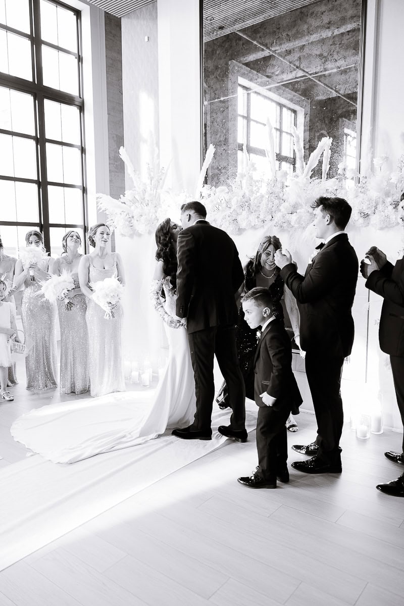 Black-and-white ceremony kiss with sequined bridesmaids, ring bearer, pampas florals and candles at The Switch House by Cescaphe, Philadelphia.