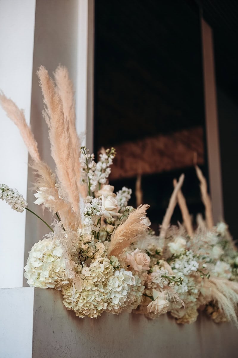 Neutral floral installation of ivory roses, hydrangeas, and pampas grass on a stone mantel at The Switch House by Cescaphe, Philadelphia.
