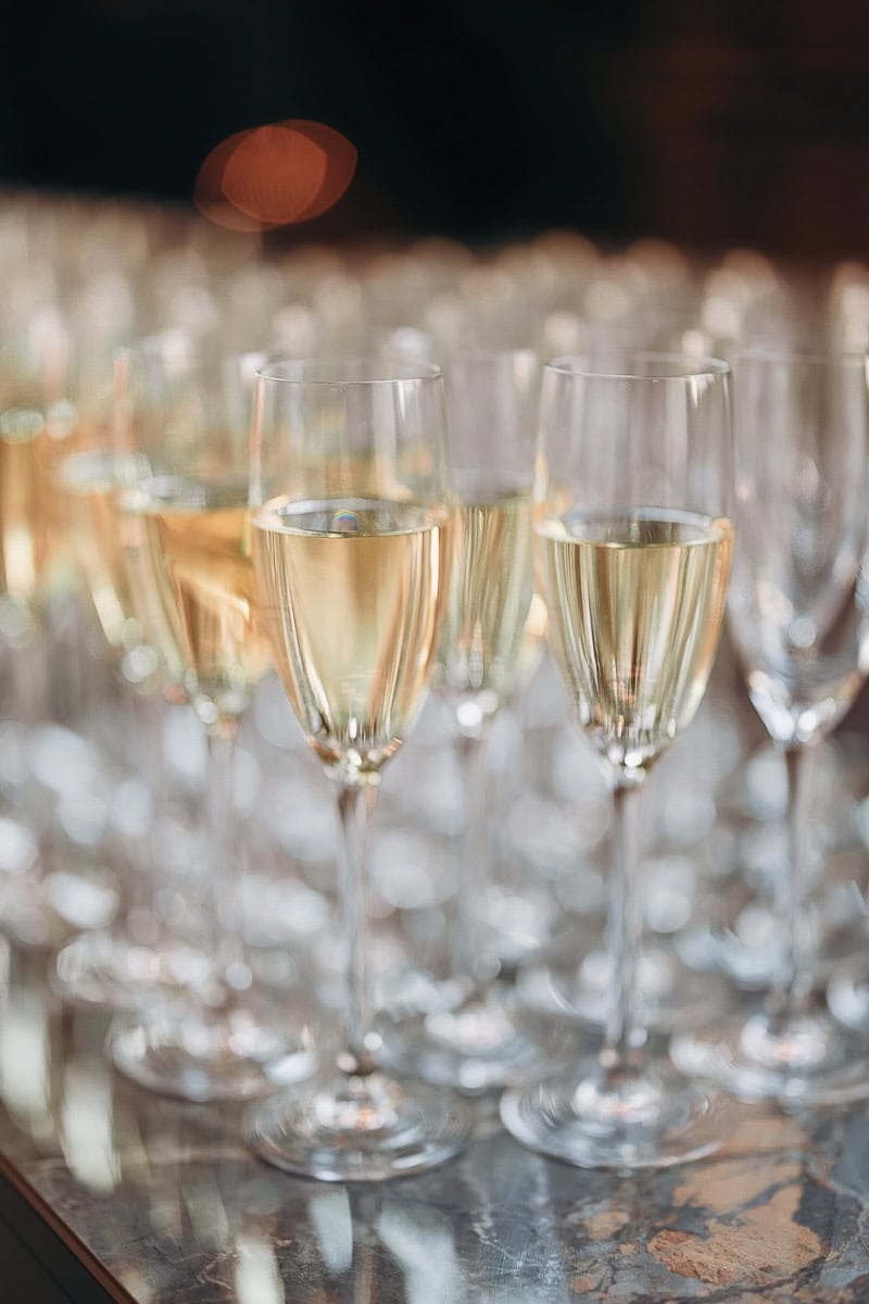 Rows of filled champagne flutes on a marble bar with soft bokeh at The Switch House by Cescaphe, Philadelphia, PA.
