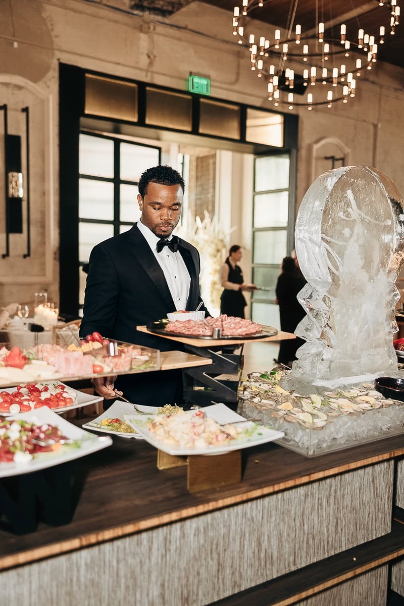 Tuxedoed guest selects charcuterie beside oyster raw bar and ice sculpture at The Switch House by Cescaphe, Philadelphia, PA.
