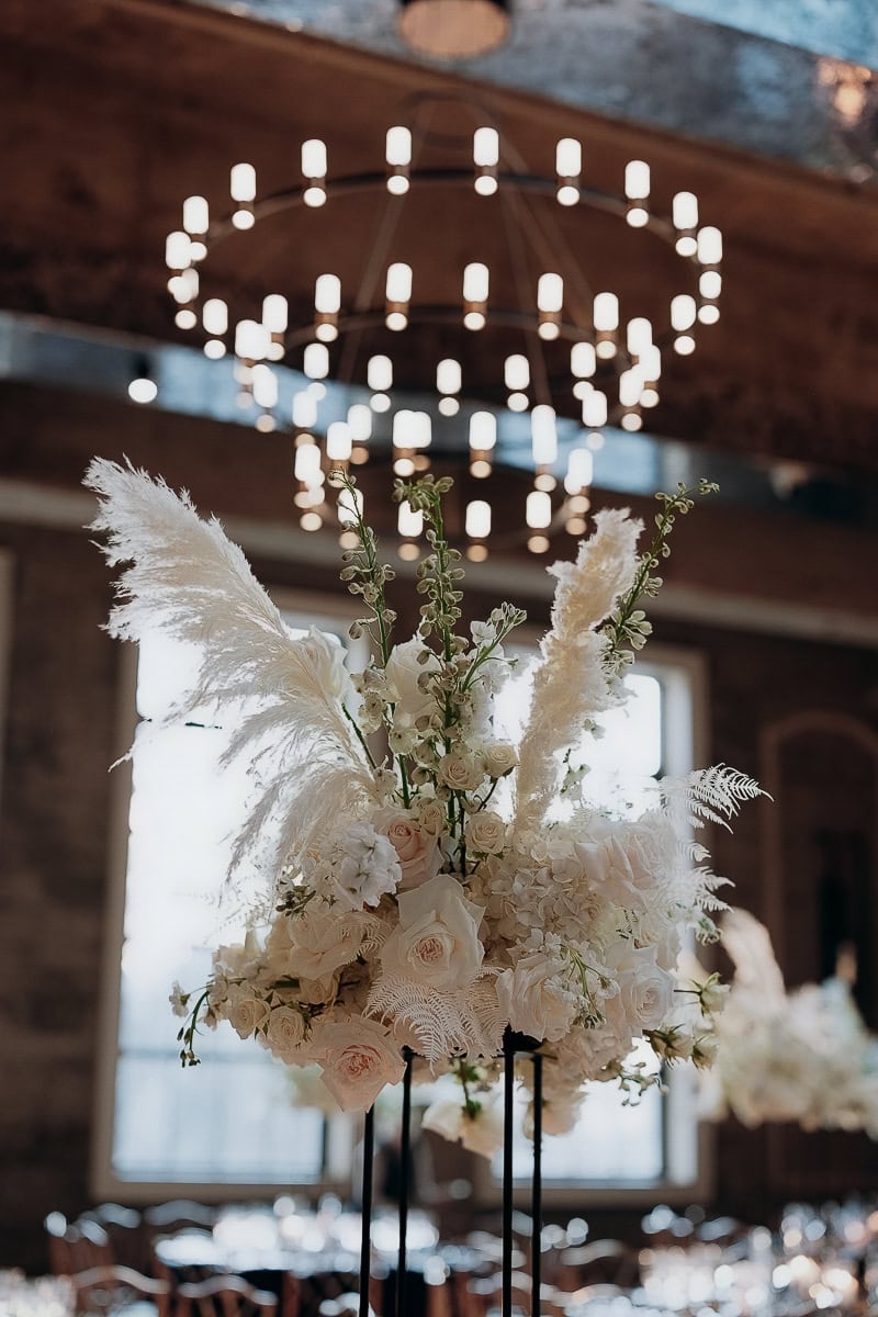 Tall white floral centerpiece with pampas on black stand, soft chandelier bokeh at The Switch House by Cescaphe, Philadelphia, PA.