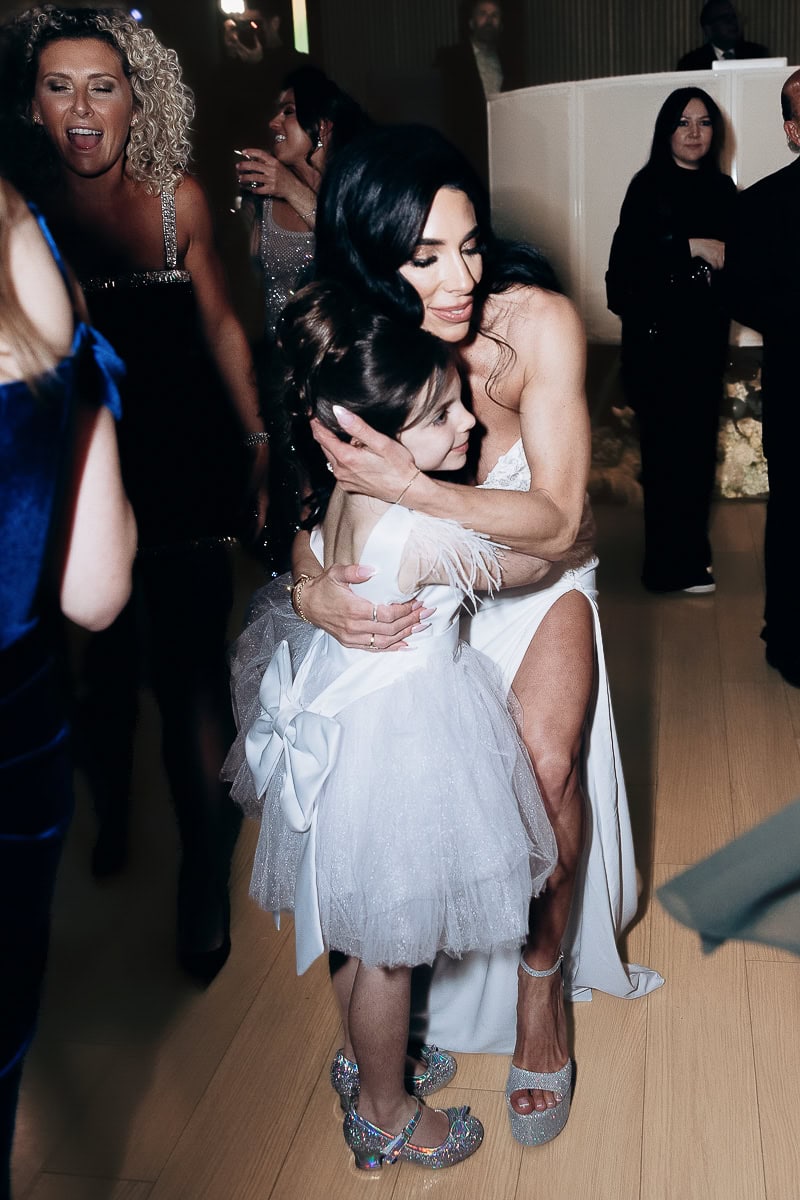 A woman in a white gown hugs a young girl in a tulle dress on a lively reception dance floor at The Switch House, Philadelphia.