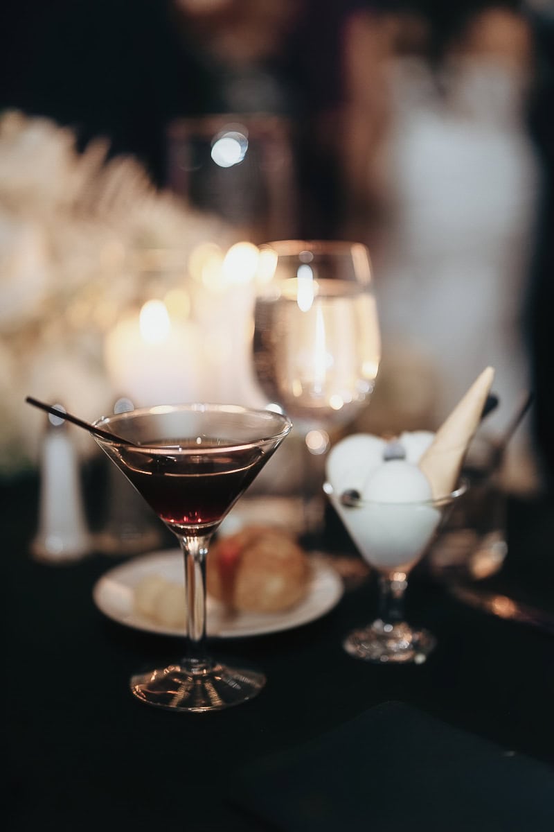 Close-up of a dark cocktail and mini sorbet dessert on a candlelit reception table with glassware and bread at The Switch House, Philadelphia.