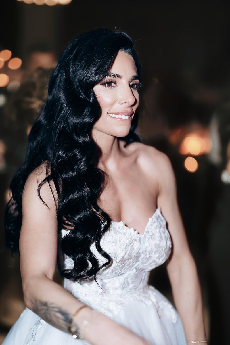 Woman in a strapless lace wedding gown with long waves, softly lit at an evening reception at The Switch House by Cescaphe, Philadelphia.