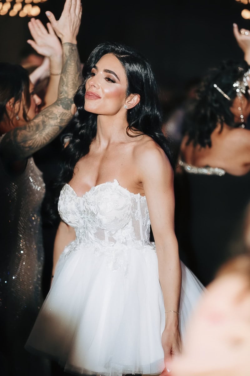 Woman in strapless lace wedding mini dress dancing under moody light at The Switch House by Cescaphe, Philadelphia, PA.
