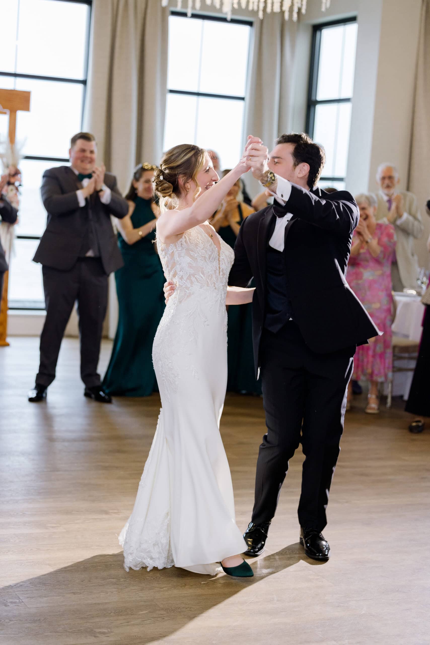 Bride and groom dancing their first dance at Tyde at Walnut Beach with guests applauding in the background.