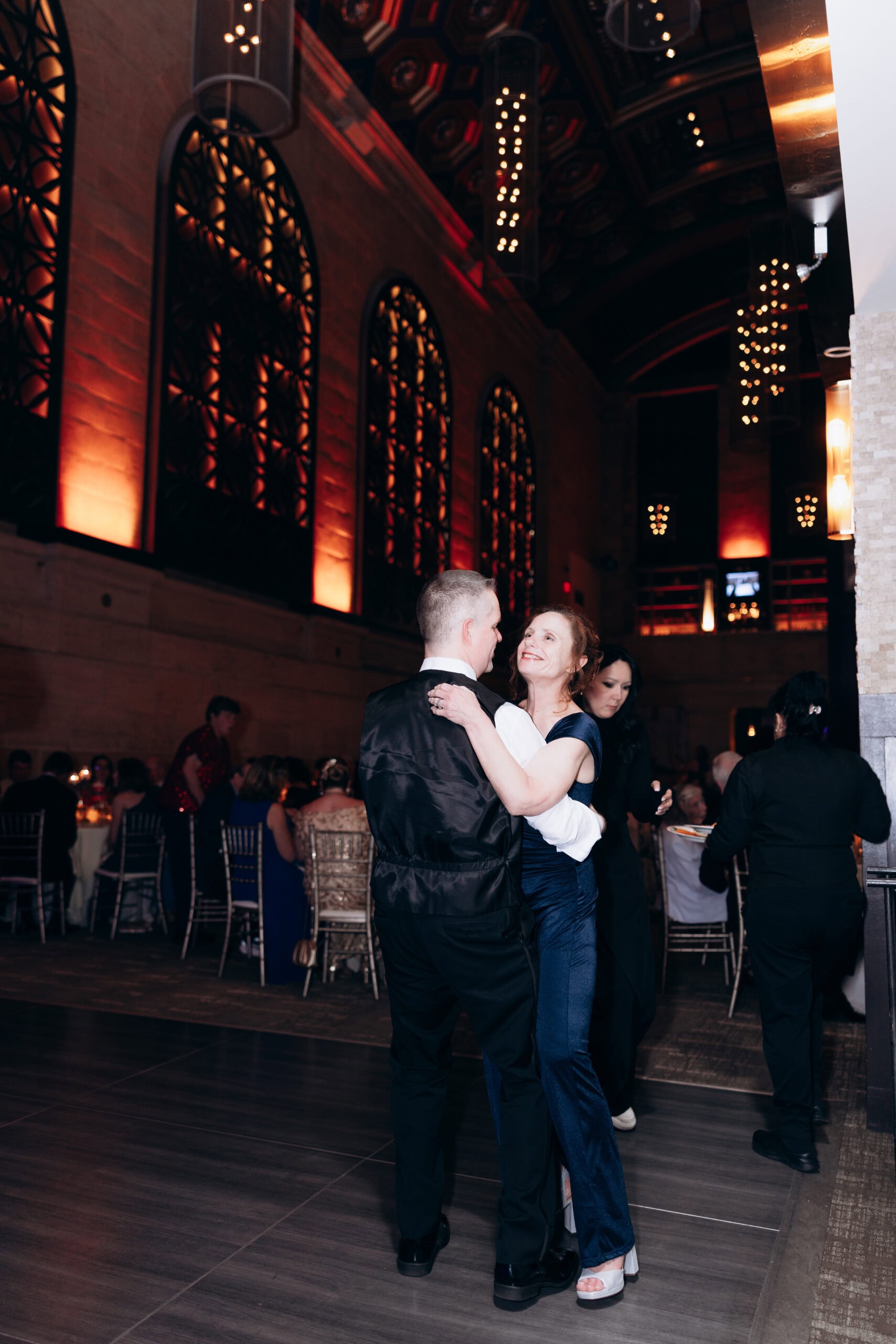 Couple dancing closely in an elegant hall with ornate arched windows and warm lighting at Union Trust, Philadelphia.