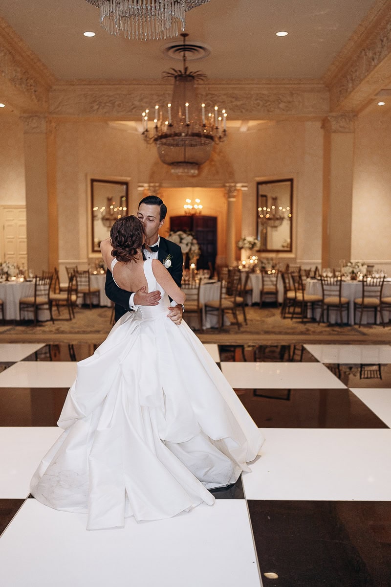 Bride and groom embracing during their first dance on a black-and-white checkered floor in an ornate ballroom at Westchester Country Club, Rye, NY.