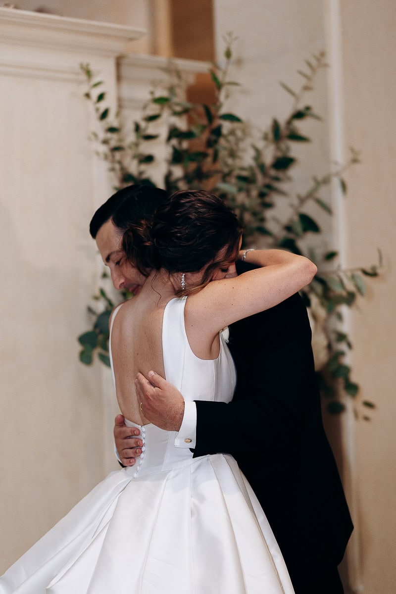 Bride and groom sharing an intimate embrace during their wedding at Westchester Country Club, Rye, NY, with the bride in a white satin gown and the groom in a black tuxedo.