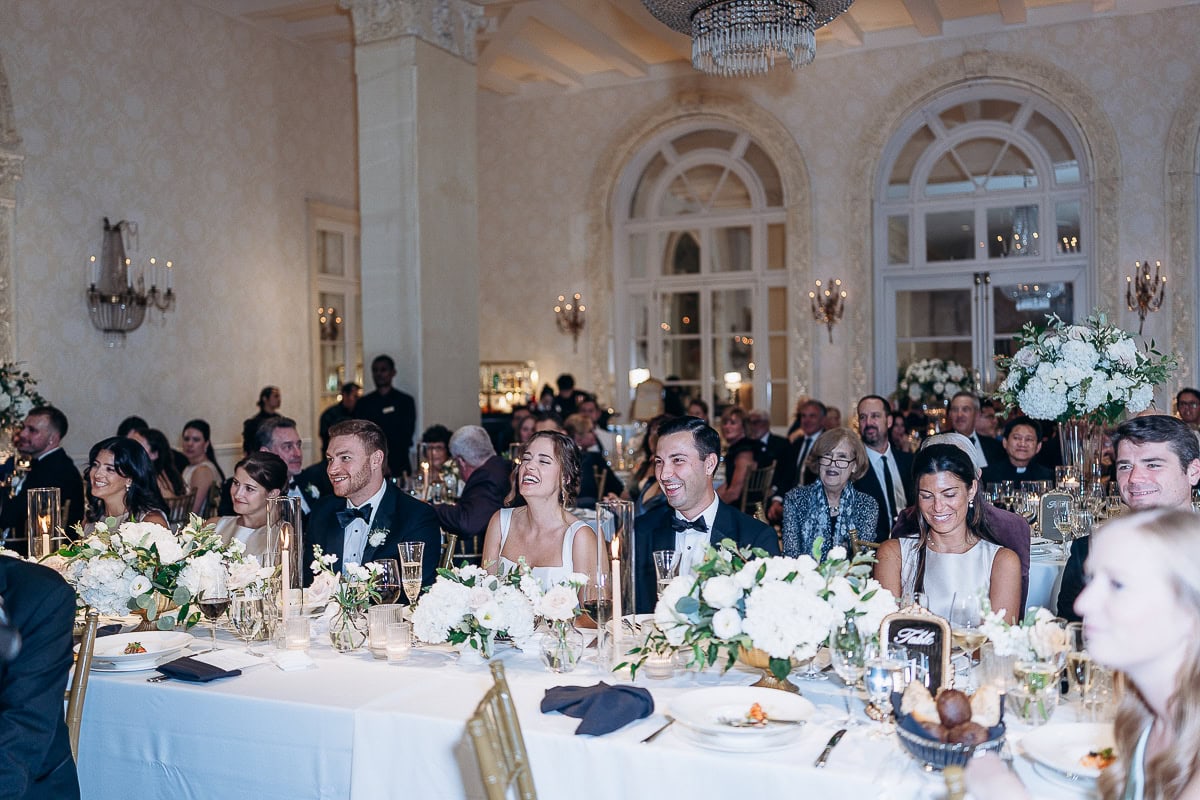 Guests seated at a long banquet table adorned with white floral centerpieces and candles in an ornate ballroom at Westchester Country Club, Rye, NY.