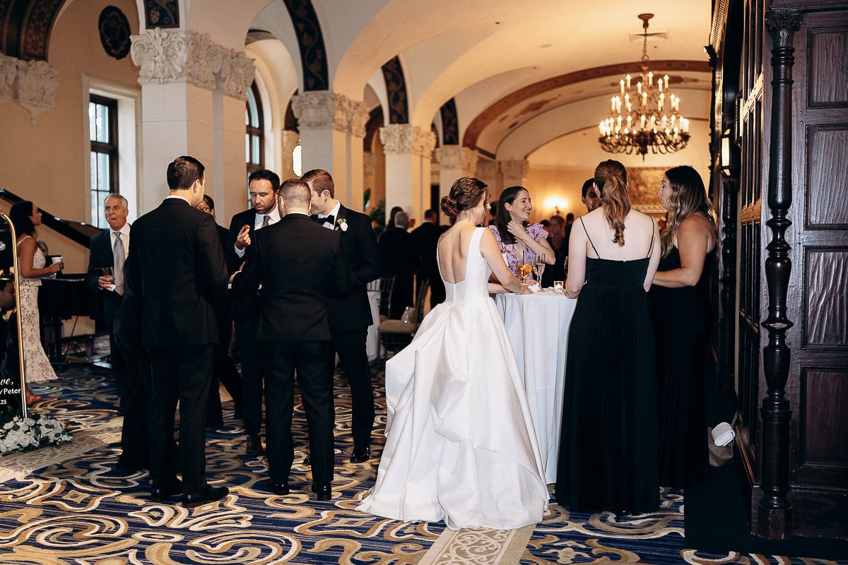 Guests in formal attire conversing in an ornate reception hall with arched ceilings and chandelier at Westchester Country Club, Rye, NY.